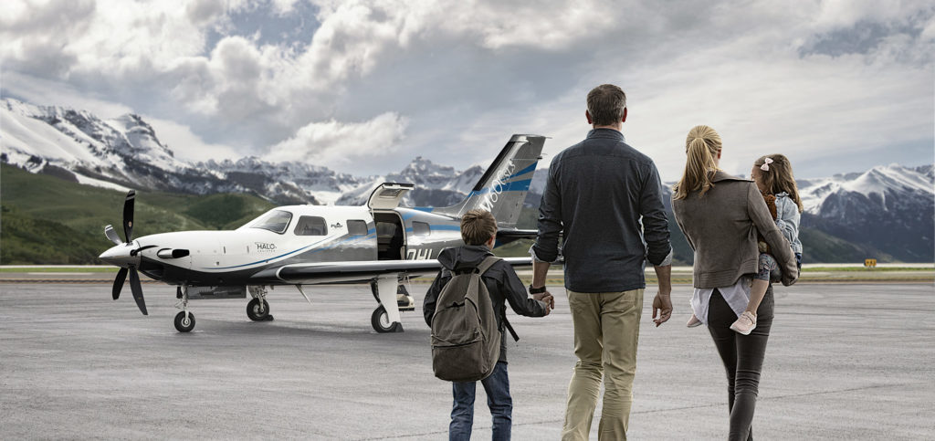 Family holding hands and walking toward a Piper aircraft