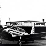 Historical photo of an aircraft in front of a Muncie hangar
