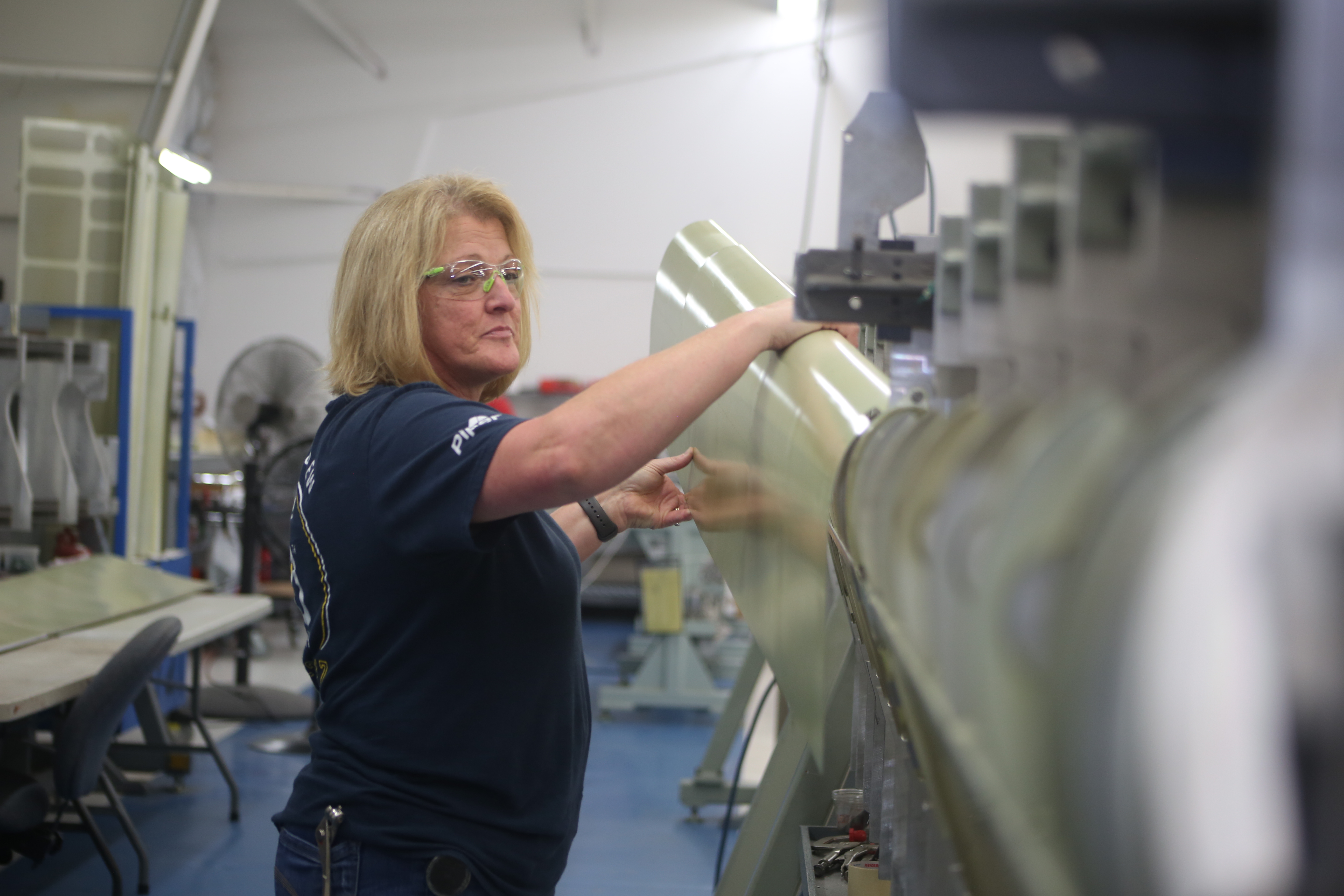 Piper Aircraft employee wearing goggles and working in a shop