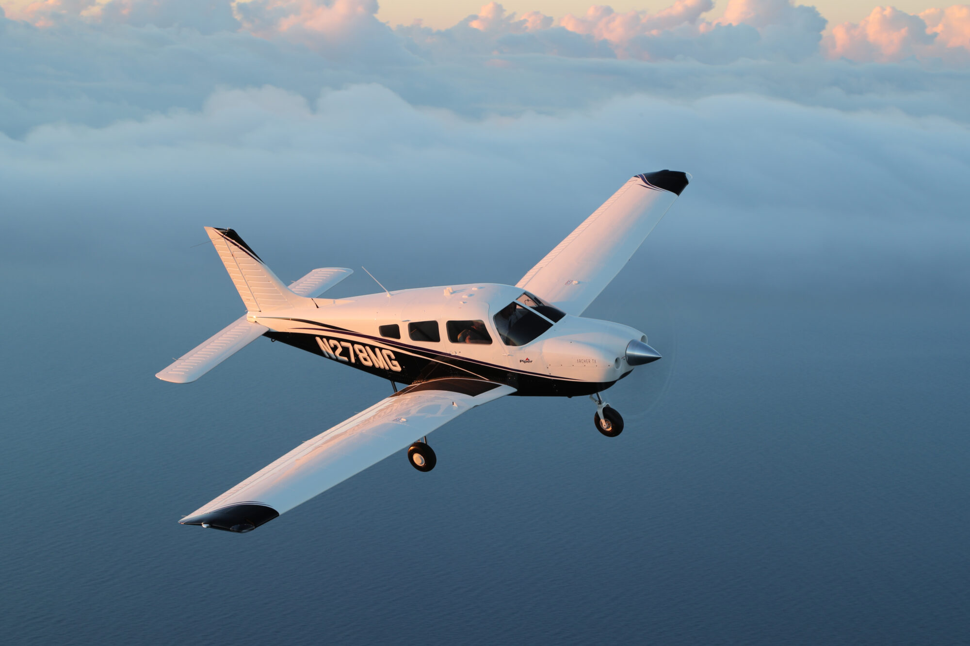 A Piper Archer trainer aircraft flying in the clouds.