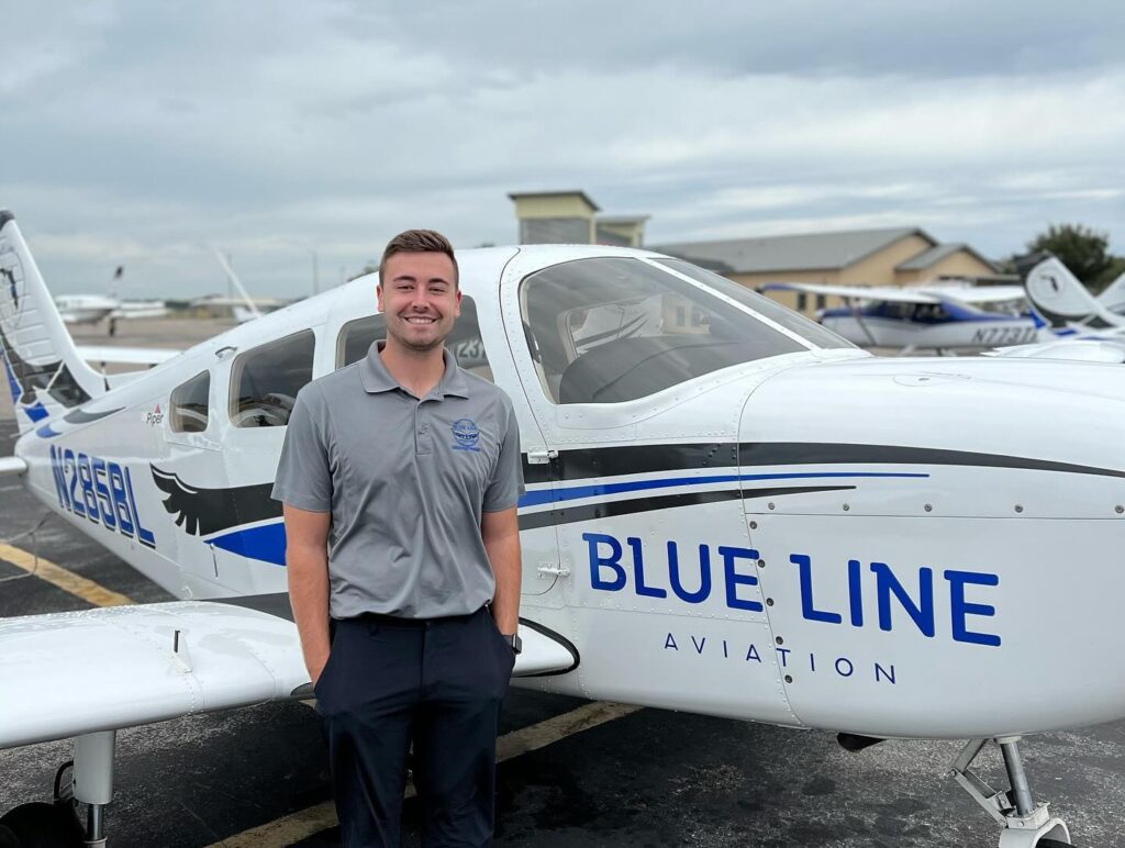 A man smiling, standing next to a plane.
