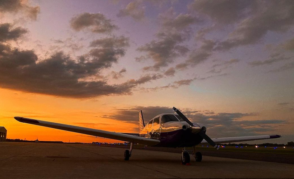 A plane on the ground with a beautiful sunset in the background