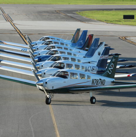 Choosing the Right Trainer Aircraft for Your Flight School 13 A fleet of Piper Archer aircraft lined up on an airport tarmac, showcasing various tail designs and school logos.