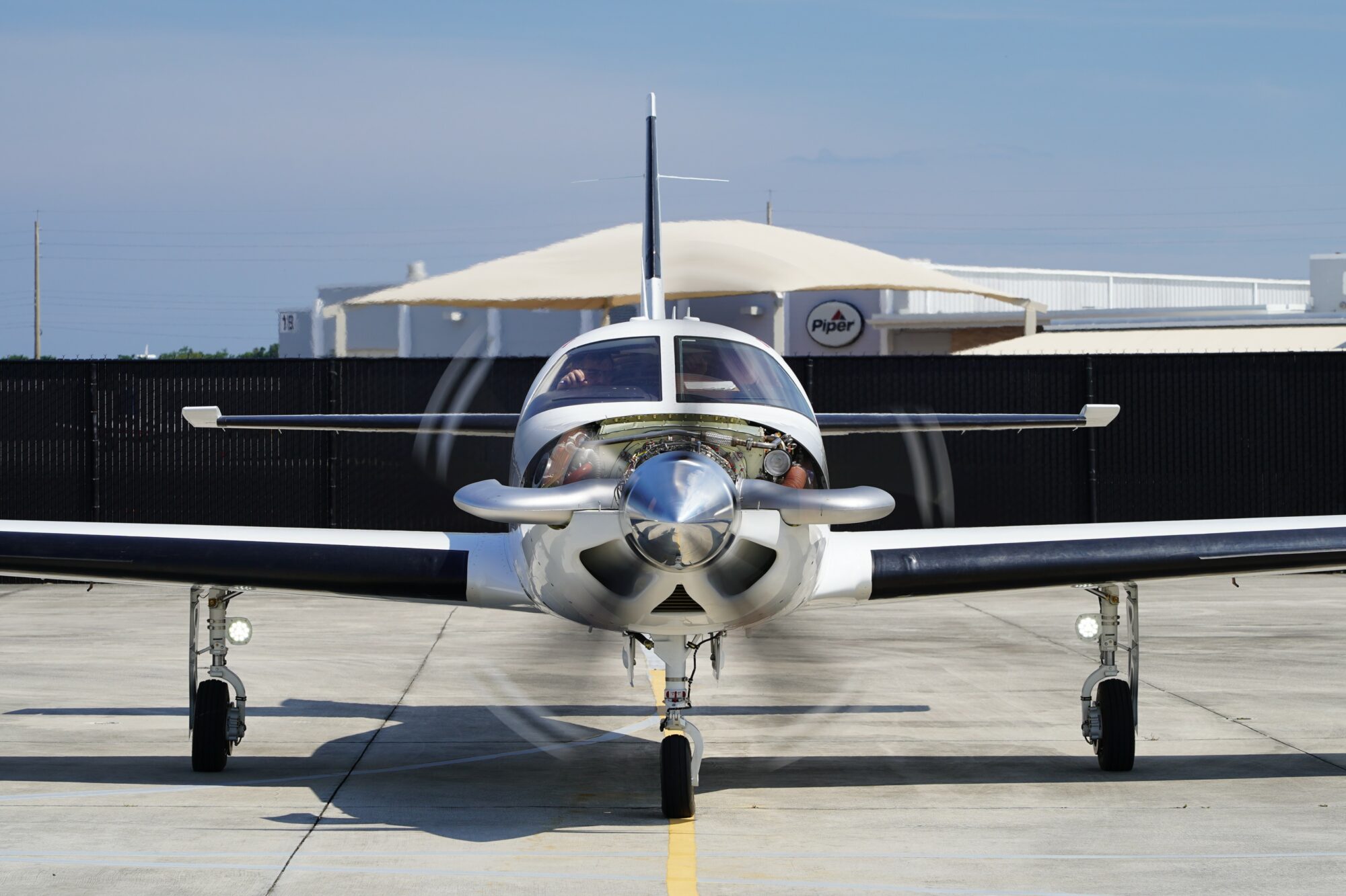 Front view of a Piper M700 with its propeller in motion, positioned on a concrete surface with a Piper logo visible in the background.