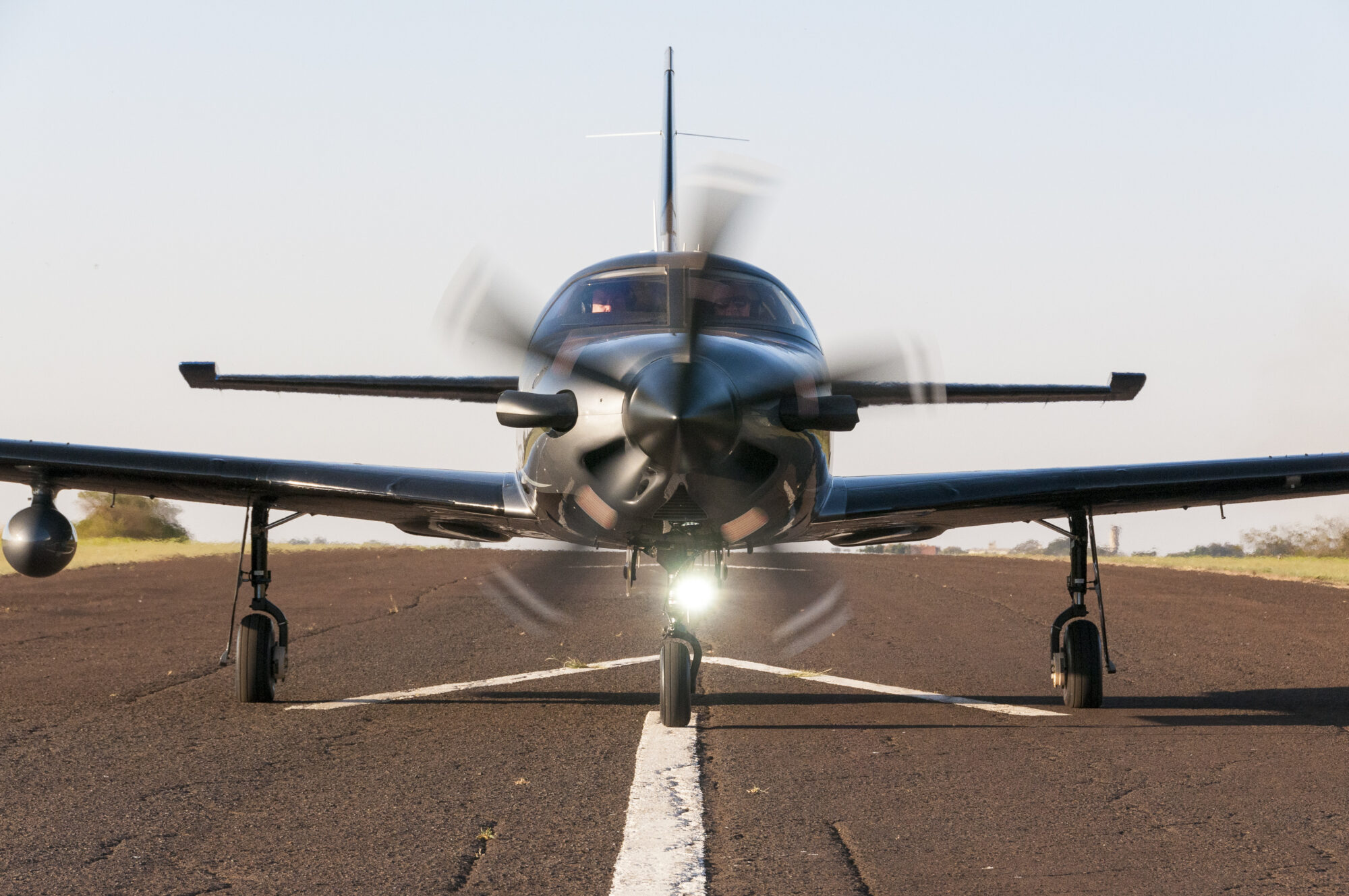 Parts of an Airplane: What Every Flight Student Should Know 2 Front view of a Piper Aircraft with its propeller spinning as it prepares for takeoff, with landing gear visible on a runway.