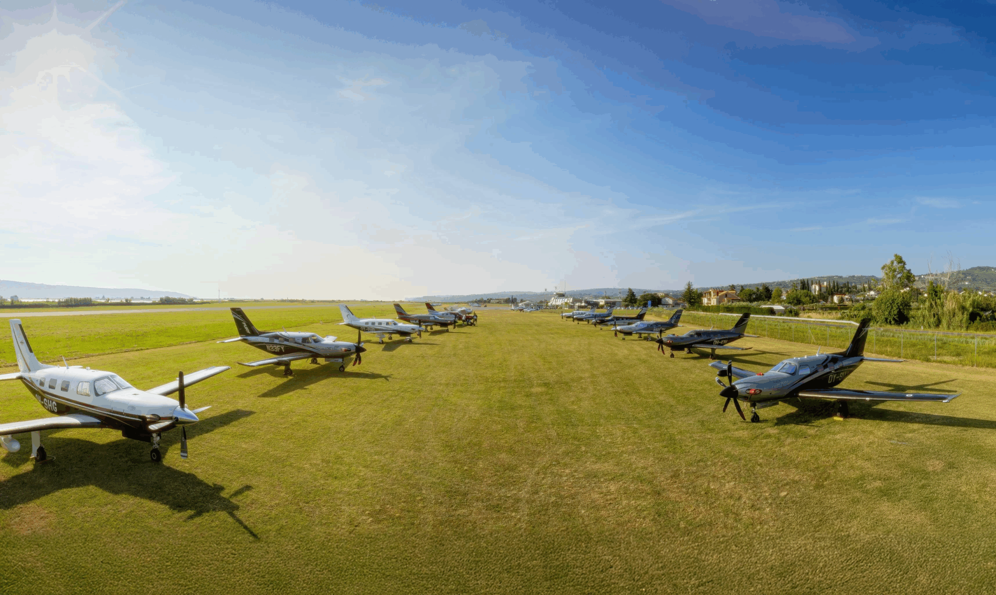 A lineup of 25 Piper aircraft parked on the grass at Portorož Airport during the European Fly-In 2025.