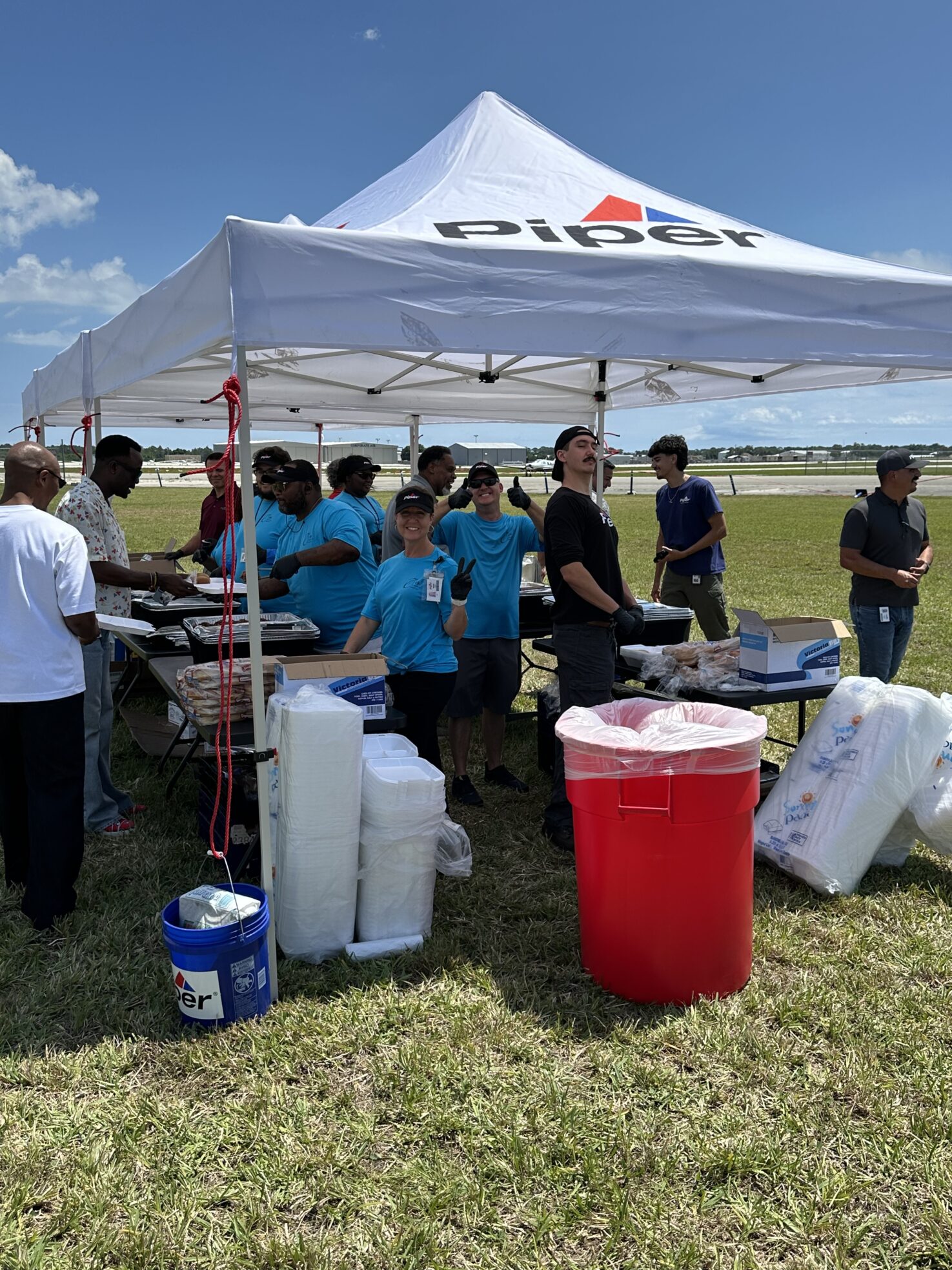 Piper Aircraft team members serve lunch to employees under a branded Piper tent on the airfield during Vero Beach Air Show practice.