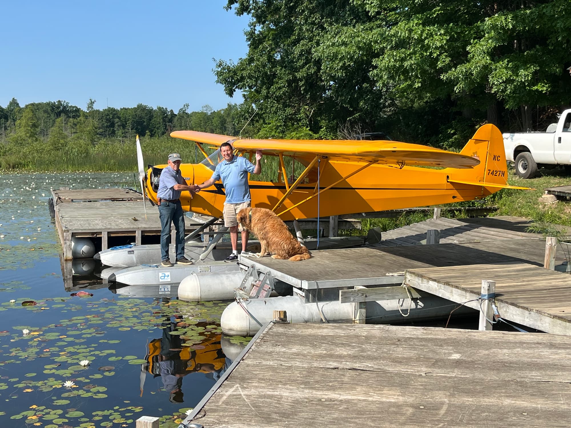 NC7427H: A Piper J-3 Cub's Journey 2 Don DeRuiter shaking hands with Piper Aircraft CEO John Calcagno in front of Don's yellow Piper J3 Cub.